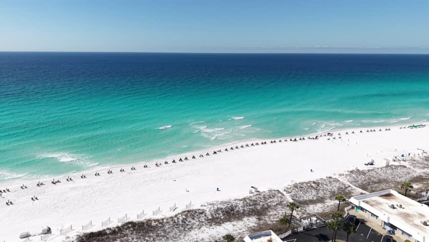 Long aerial coastline of emerald Gulf water and white sandy beach stretching into distant horizon, 30A, Florida, USA