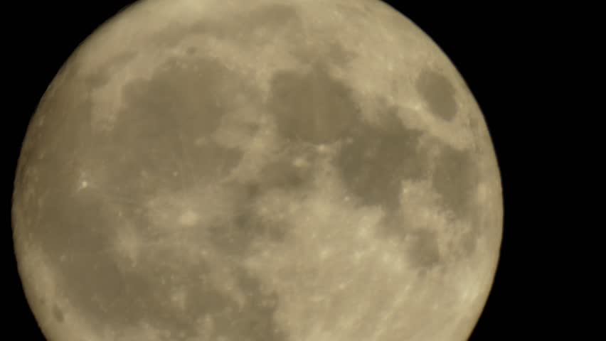 Extreme close up of full moon moving slowly through dark night sky with visible craters and lunar surface