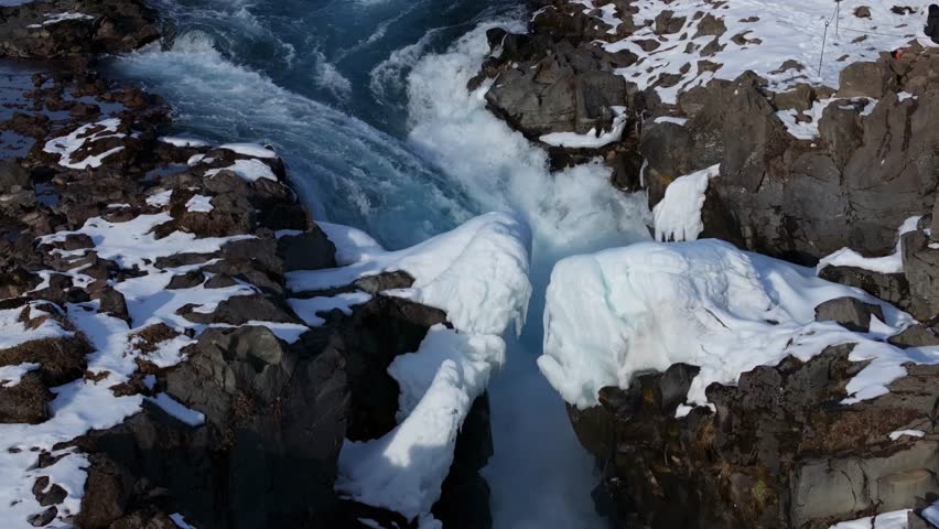 Aerial view of turquoise Bruarfoss torrent cutting snowy canyon rocks