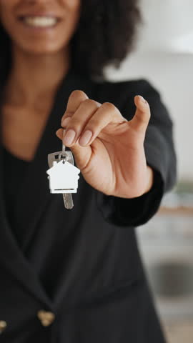Woman real estate broker holding keys of new apartment in hands, closeup view. Elderly spouses discussing buying new house or flat, make decision about mortgage, homeowner in blurred background