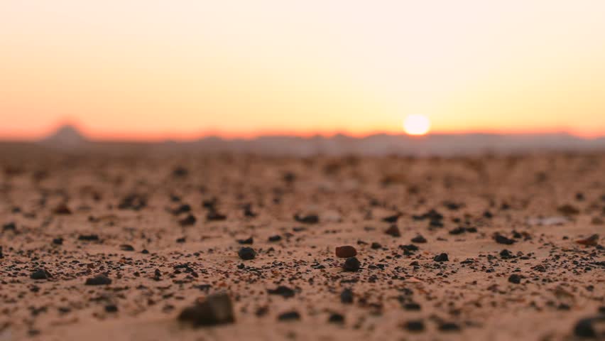 Close Up Black Volcanic Rocks on Golden Desert Sand at Sunset