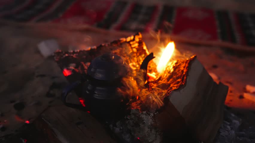 Close Up and Tea Kettle inside Glowing Campfire Embers and Flames at Night in Bedouin Desert Camp Egypt