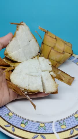 Sukabumi Regency, Indonesia - Close up of Blue plate holds traditional rice dish. Crispy, browned chunks sit beside soft white rice. Woven palm leaf bundle adds cultural touch. Bright blue background highlights the food