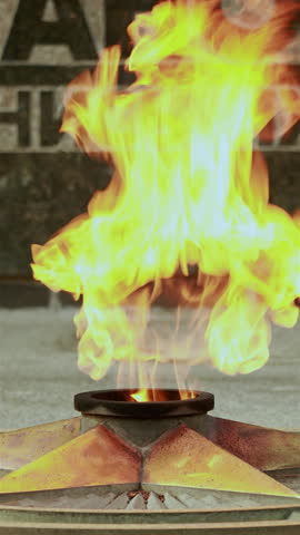 Bright eternal flame burning on bronze star memorial monument. Vertical.