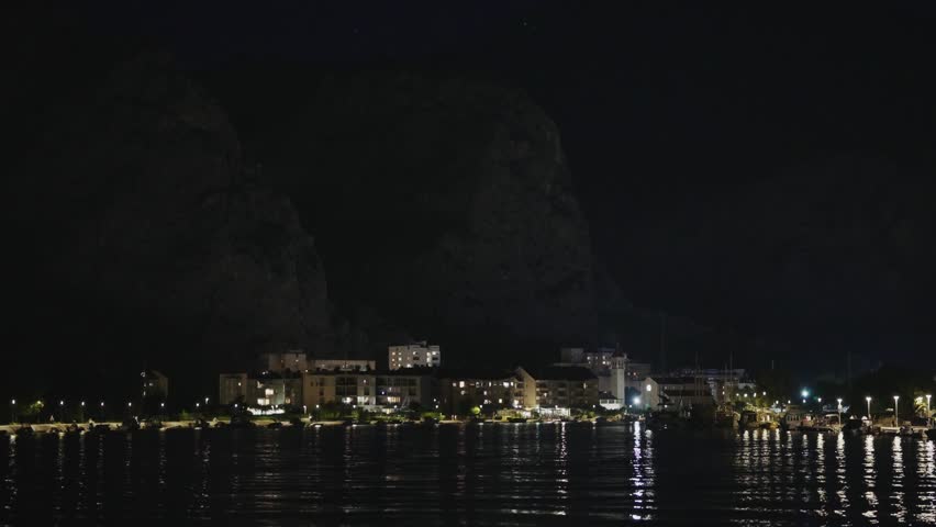 Night view of a coastal Mediterranean city with illuminated lights.