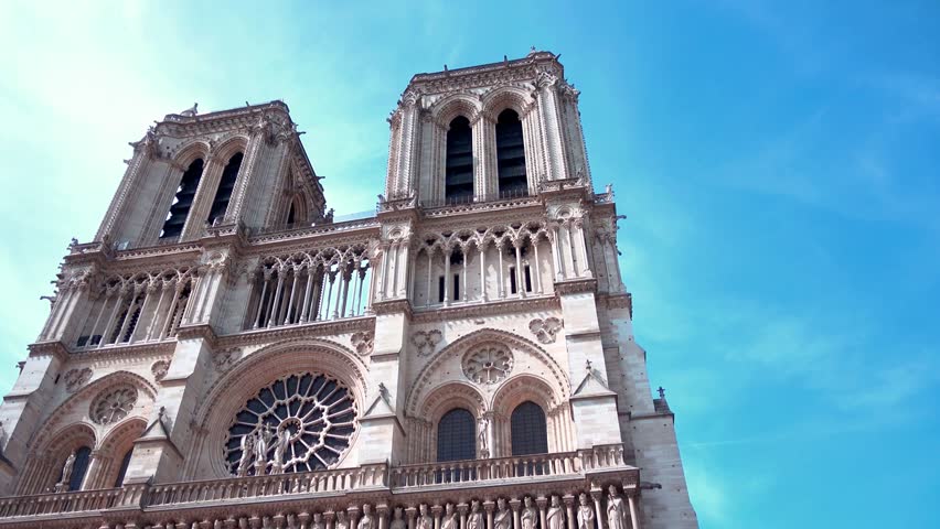 Captivating view of Notre-Dame Cathedral in Paris, with twin towers, rose window, and Gothic details against blue sky. Iconic French landmark for travel and history footage.