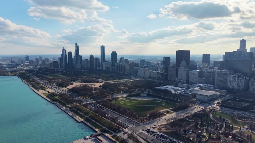 An expansive aerial perspective of the Chicago skyline, featuring the iconic Park and the serene blue waters of Lake Michigan on a sunny day.