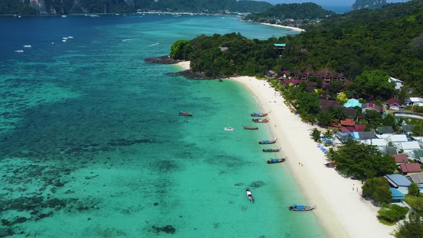 Drone aerial views of Phi Phi Island including Long Beach, turquoise waters, tropical coastline and traditional longtail boats.