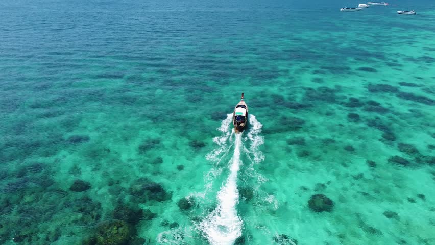 Drone aerial views of Phi Phi Island including Long Beach, turquoise waters, tropical coastline and traditional longtail boats.