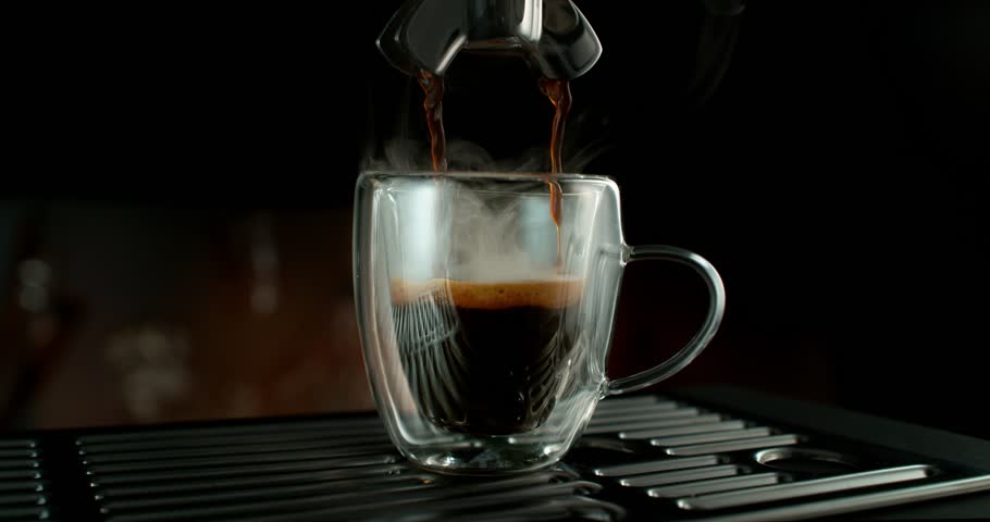Super slow motion shot of espresso pouring into a glass cup with a slow orbital camera movement. Rich crema forms as the camera circles the cup, creating a cinematic coffee scene with depth and detail.