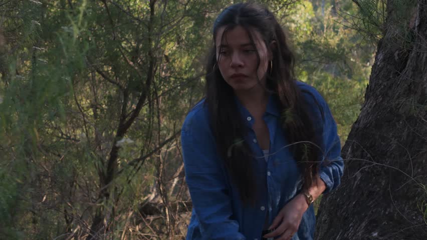 A young woman adventuring through thick foliage in the Warrendyte mining area of Melbourne. Natural light filters through trees, creating a serene yet mysterious atmosphere.