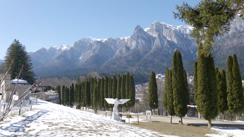Winter landscape of the snow-covered Bucegi Mountains rising above the town of Busteni, Romania. Scenic Romanian nature and countryside atmosphere.