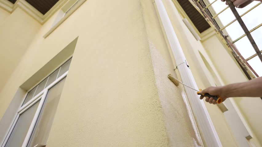 Man Painting House Exterior with Roller
