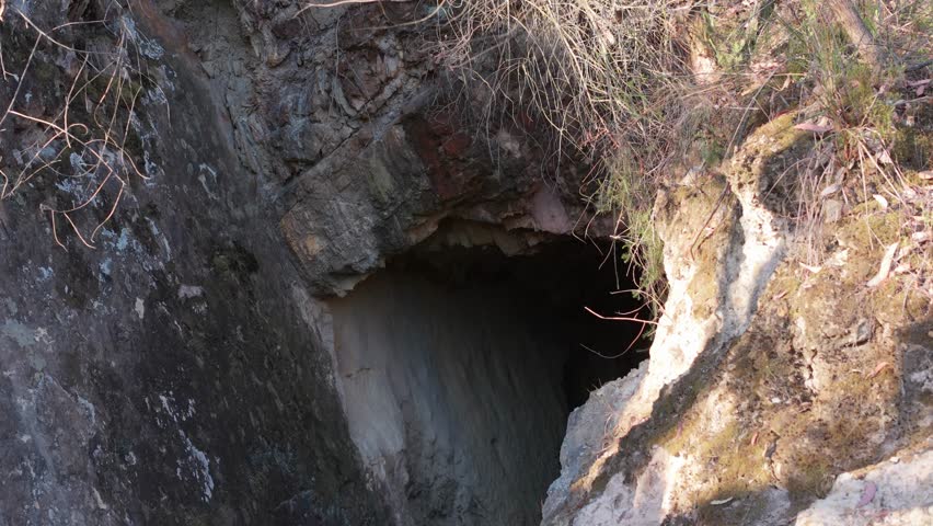 Explore the rugged entrance of an abandoned mine tunnel in Warrendyte Mountain, Melbourne. Captured in golden sunlight, the rock face and surrounding flora create a mysterious and inviting scene.