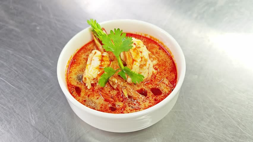 A bowl of Tom Yum Goong, famous Thai seafood soup with shrimp and mushrooms.