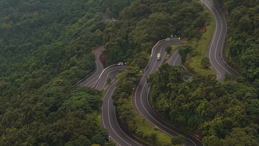 Aerial drone shot of the famous 18 hairpin bends winding through lush tropical mountains and dense forest in Sri Lanka.