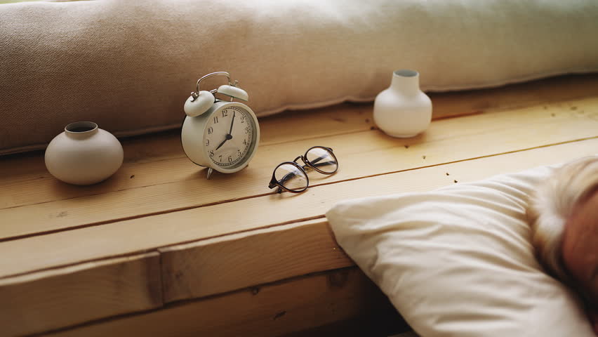 Happy senior female waking up in cozy bed and stretching, morning energy