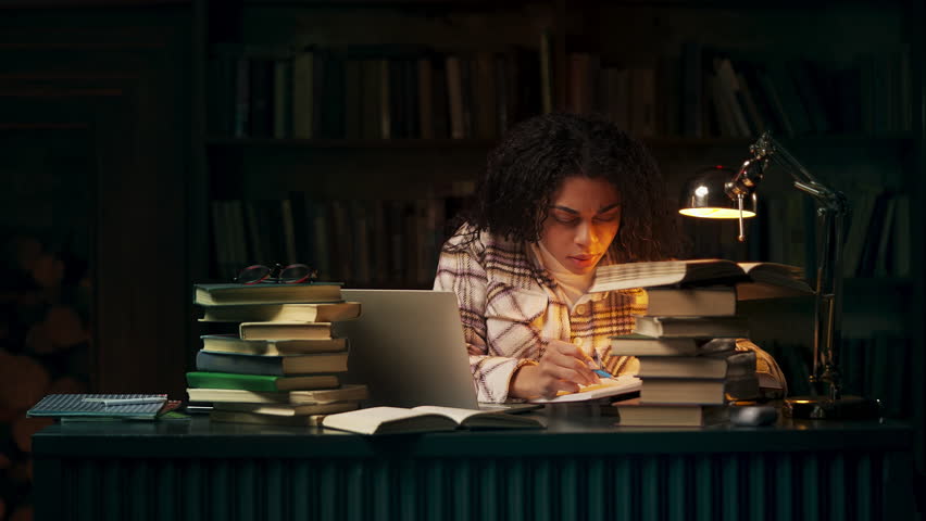 Concentrated African American student researching in library during late night