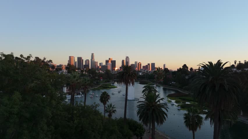 Aerial flight over Echo Park Lake with palm trees toward Downtown Los Angeles skyline, November 25 2025