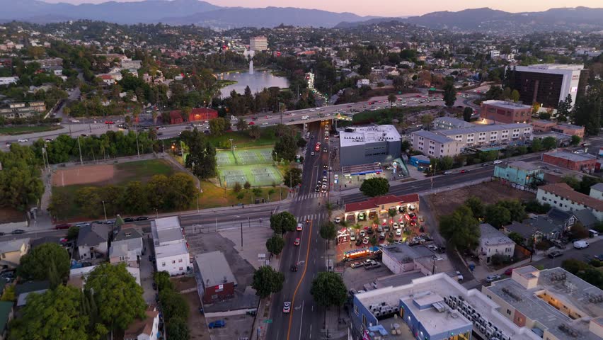 Drone flight over freeway and Echo Park Lake in Los Angeles at sunset with city traffic, November 25 2025