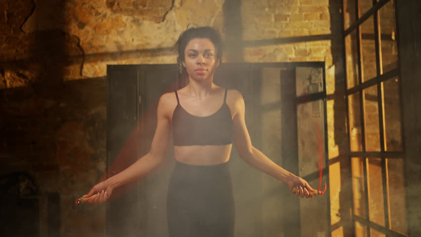 Black female athlete exercising with jumping rope in gym during intense workout