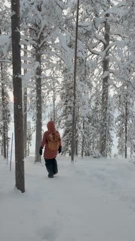 A serene adventure in Akaslompolo, Finland as visitors wander through a snowy forest, surrounded by tall trees adorned with frost. The tranquil beauty of winter captivates all.