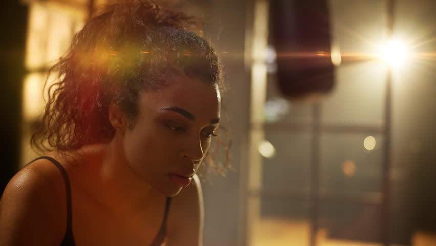 Young African American woman wiping sweat after intense cardio training in gym