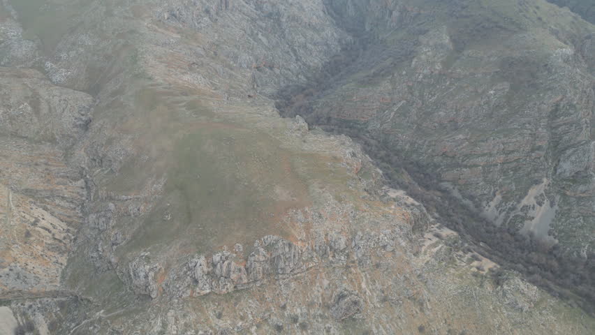 High-angle shot of rocky, mountainous terrain with sparse green vegetation.