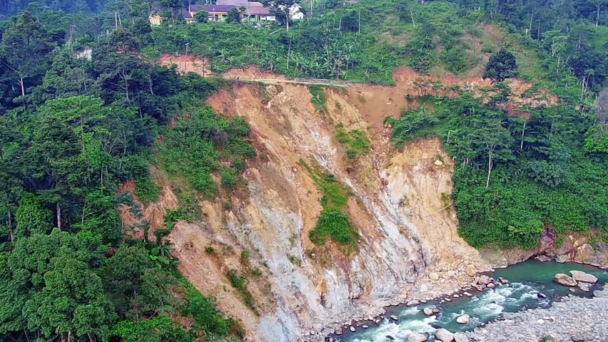 A large landslide on a cliffside next to a body of water