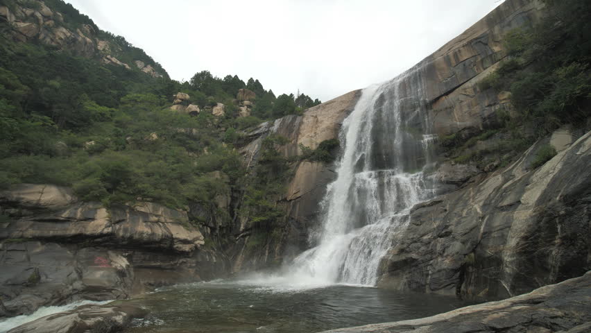 The waterfall has a rapid flow and splashes of water.