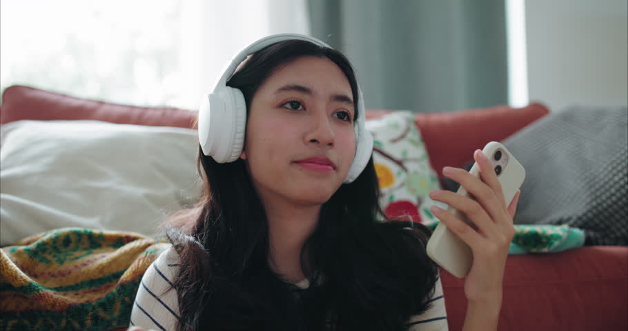 Happy Young Asian Woman Listening to Music with Headphones and Dancing Gently at Home	