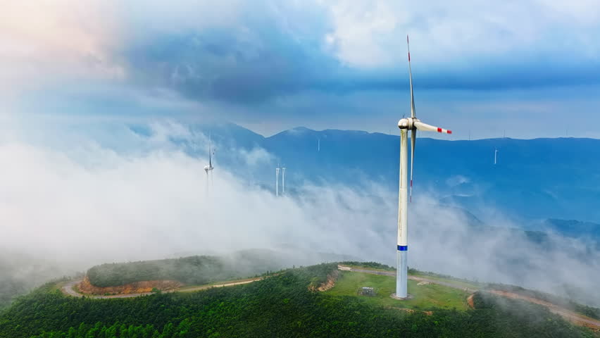 Wind farm on mountain ridges under a cloudy sky. Renewable energy concept.