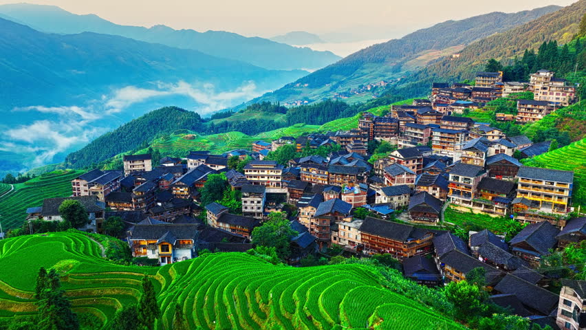 Aerial view of Longji rice terraces and a large traditional ethnic village on a mountain slope in Guilin, China.