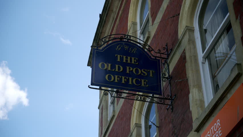 Sign of the Old Post Office in a historic area during daytime with blue sky and clouds