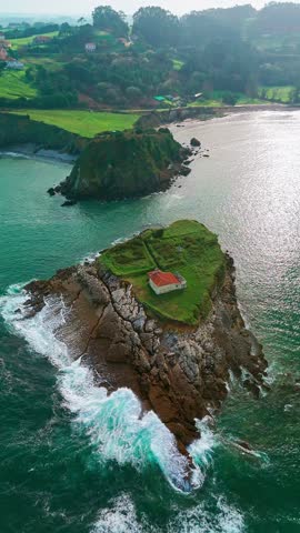 Aerial view of Ermita de El Carmen, a small chapel situated on a rocky island in the Cantabrian Sea near Luanco, Asturias, Spain. A scenic coastal landscape in northern Spain.