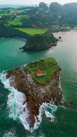 Aerial view of Ermita de El Carmen, a small chapel situated on a rocky island in the Cantabrian Sea near Luanco, Asturias, Spain. A scenic coastal landscape in northern Spain.