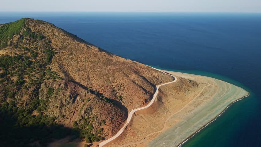 Samothrace, Greece. Aerial view of the winding coastal road along the eastern shore leading to the remote Kipos beach with dramatic high cliffs and the blue Aegean Sea.