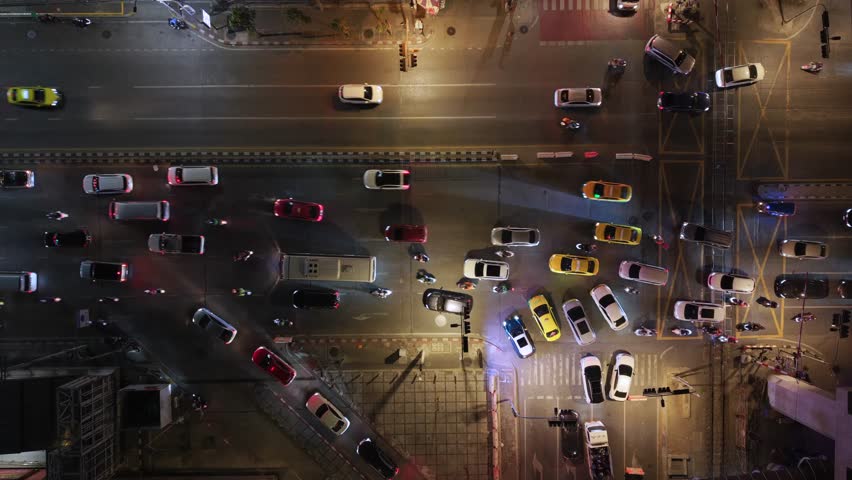 Top down aerial view of night traffic in Bangkok, Thailand with taxis and cars at busy intersection. Urban congestion and city life in Southeast Asia.