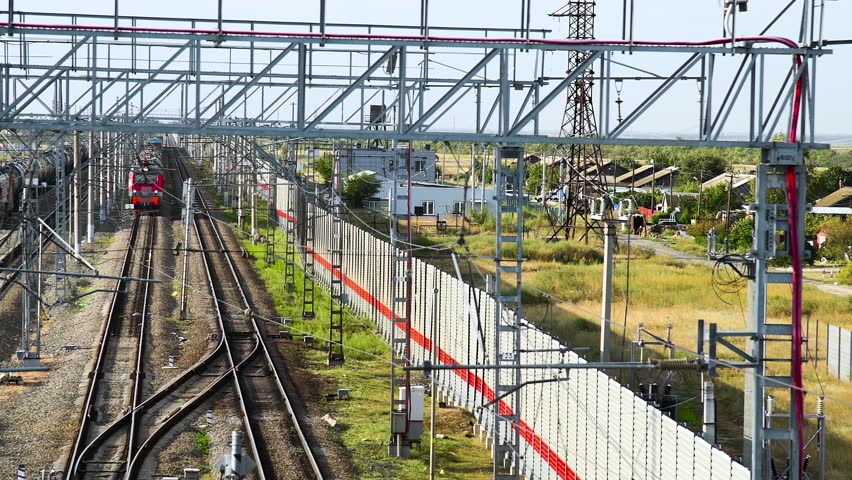 A busy railway station or junction. Trains are moving along the tracks. A large number of rails with forks and arrows creates a complex network. Railway activity