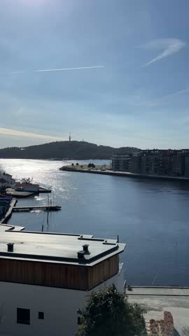 Modern waterfront cityscape with harbor, residential buildings and sunlight reflections