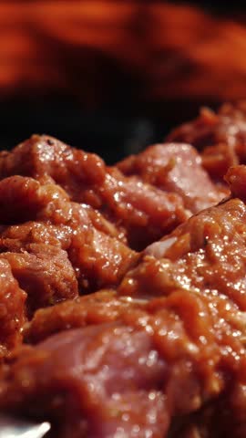 Raw meat on skewer, close up. Pork slices on barbecue. Cooking process. Vertical video