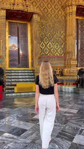 Woman walking inside Grand Palace complex near Wat Phra Kaew in Bangkok, Thailand. Golden temple architecture, cultural travel and spiritual atmosphere in Southeast Asia.