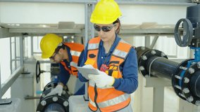 Professional female engineer using a tablet and walkie-talkie at an industrial site while a male colleague works on pipes. Expert teamwork and maintenance in a modern utility plant facility setup. - Powered by Shutterstock - Get 15% off with code: PIKWIZARD15