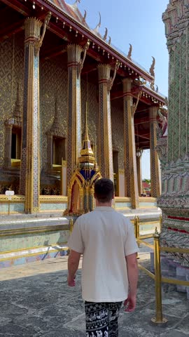 Man walking inside Grand Palace complex near Wat Phra Kaew in Bangkok, Thailand. Traditional Thai temple architecture and cultural travel experience in Southeast Asia.