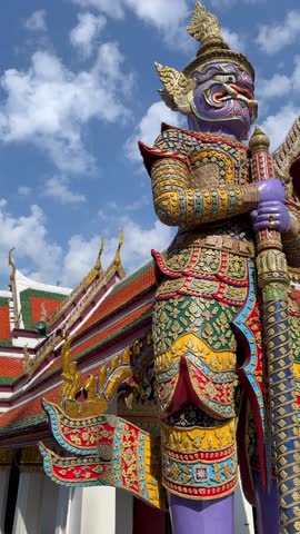 Low angle view of giant guardian statues at Thai temple in Bangkok, Thailand. Colorful traditional architecture and cultural heritage in Southeast Asia.