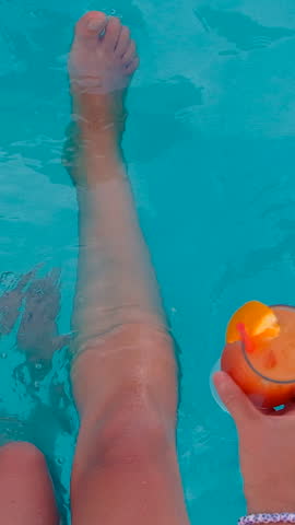 Woman in the pool with a cocktail. Selective focus.