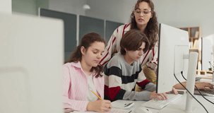 Teacher helps teenagers with computer classroom project. Students take notes as the instructor guides a lesson promoting learning and study focus. Clear teamwork education study concept. - Powered by Shutterstock - Get 15% off with code: PIKWIZARD15