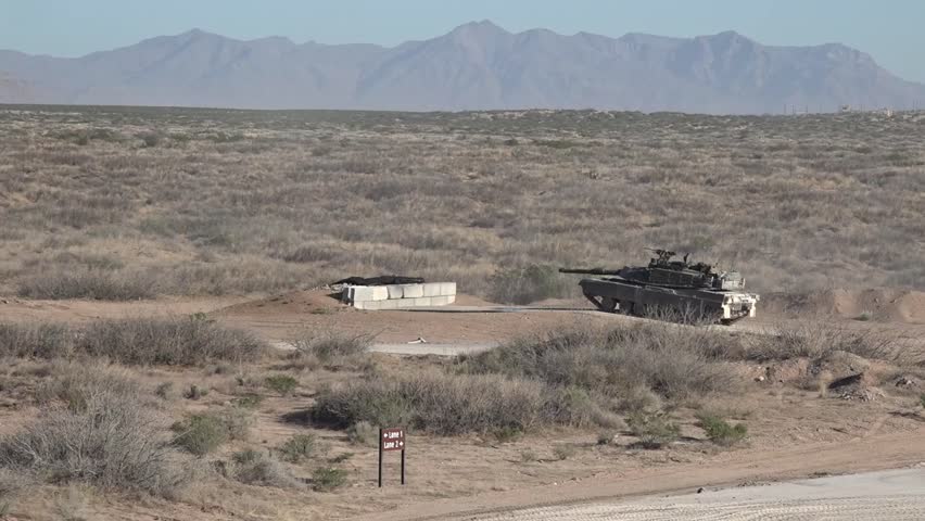 U.S. Army M1A2 Abrams Main Battle Tank firing its 120mm M256 smoothbore gun during a live-fire training exercise at a military range