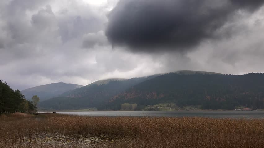 Stunning Timelapse of Gloomy Storm Clouds Over Autumn Winter Forest Lake. Dramatic Weather Transition Across Mountain Wetlands, Desolate Water, and Serene Wilderness Area.
