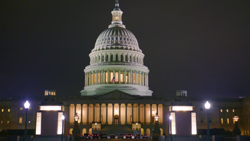 US Capitol glowing at night. Capitol dome illuminated. Washington DC landmark at night. US Capitol building in darkness. Iconic dome shining at night. Night view of Capitol Hill.
